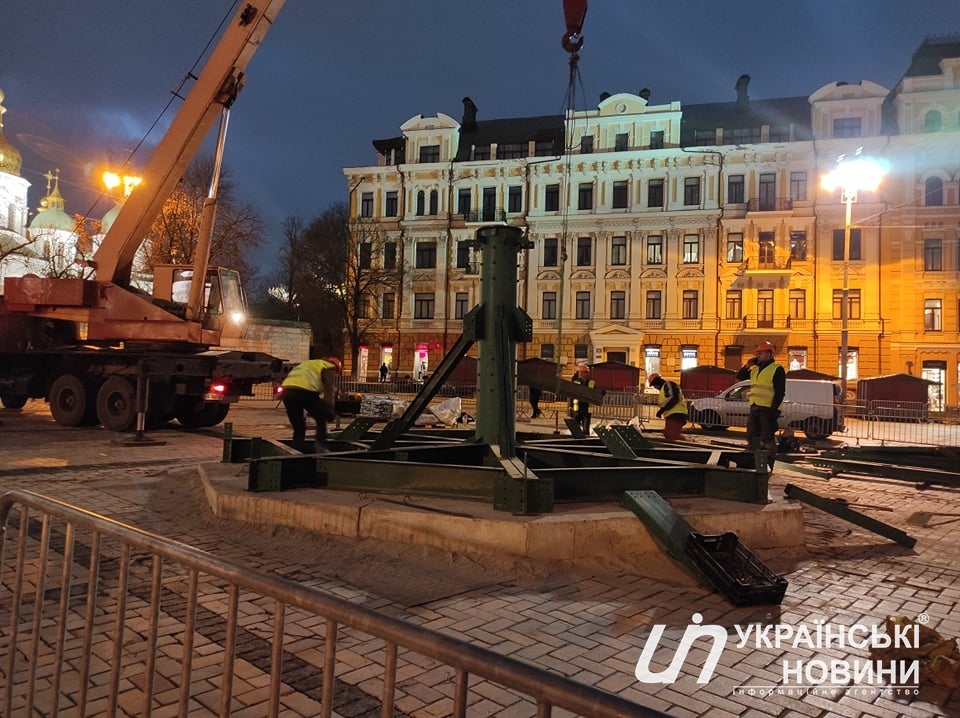 Кран и рабочие устанавливают главную елку страны на Софийской площади в Киеве вечером 26 ноября