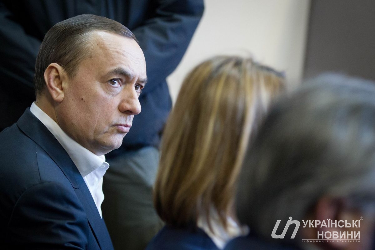 Сам Мартыненко находится не в клетке для задержанных, а на лавке с адвокатами