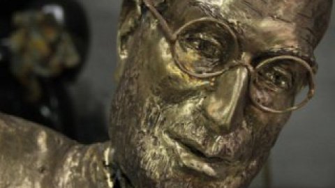 Бронзовий Джобс одягнений у водолазку, джинси, кросівки, а на його обличчі круглі окуляри.