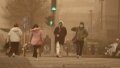 People wearing face masks walk in dust in Beijing, capital of China, March 15, 2021. Photo by Xinhua/Ju Huanzong.