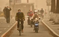 People wearing face masks ride in dust in Beijing, capital of China, Photo by Xinhua/Li Xin.
