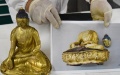 A staff shows a restored gold-plated bronze Buddha statue. Photo by Xinhua/Ding Lei
