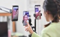 A young woman sells clothes in front of phone cameras via livestreaming on an e-commerce platform. Photo by Xinhua/Liu Dawei.