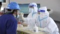 A medical worker collects a swab sample from a worker for nucleic acid tests at Harbin Electric Corporation. Photo by Xinhua/Zhang Tao.