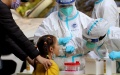 A medical worker from east China's Zhejiang Province takes a swab sample from a child for nucleic acid test at a community in Songjiang District of Shanghai. Photo by Xinhua/Liu Ying.