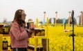 A staff member promotes and sells rapeseed oil via livestreaming amid cole flowers in Longquan Village in Anzhou of Mianyang, southwest China's Sichuan Province.  Photo by Xinhua/Jiang Hongjing.