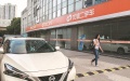 A pedestrian walks past an outlet of Uxin, a used car dealing platform, in Shanghai. Photo by Xinhua.
