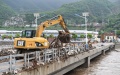 An excavator removes debris and litter from a bridge in Shuiyuzui Village in flood-hit Mentougou District, Beijing, capital of China. Photo by Xinhua/Ju Huanzong.