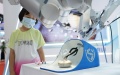 A girl looks at a surgery robot during an expo of the World Robot Conference  in Beijing, capital of China. Photo by Xinhua/Ren Chao.