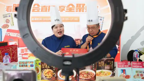 Staff members of Quanjude, one of China's best-known roast duck chain restaurants, sell products via a live show at the cultural and tourism services exhibition hall in the Shougang Park in Beijing. Photo by Xinhua/Ju Huanzong.