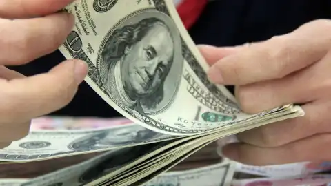 A worker counts the U.S. dollars at a bank in Tancheng County of Linyi City, east China's Shandong Province. Photo by Xinhua/Zhang Chunlei.
