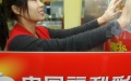 A staff member puts up posters at a lottery booth in Nantong, east China's Jiangsu Province. Photo by Xinhua/Xu Congjun.
