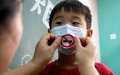 A community worker helps a child to wear a face mask with anti-smoking sign. и Photo by Xinhua.
