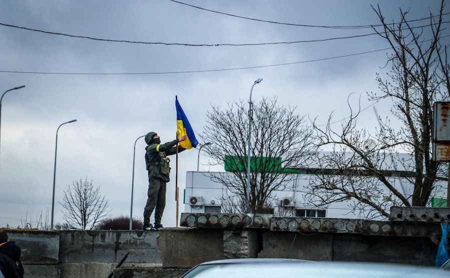 Український військовий здіймає прапор України в селі Лук'янівк Київської області. Фото з відкритих джерел