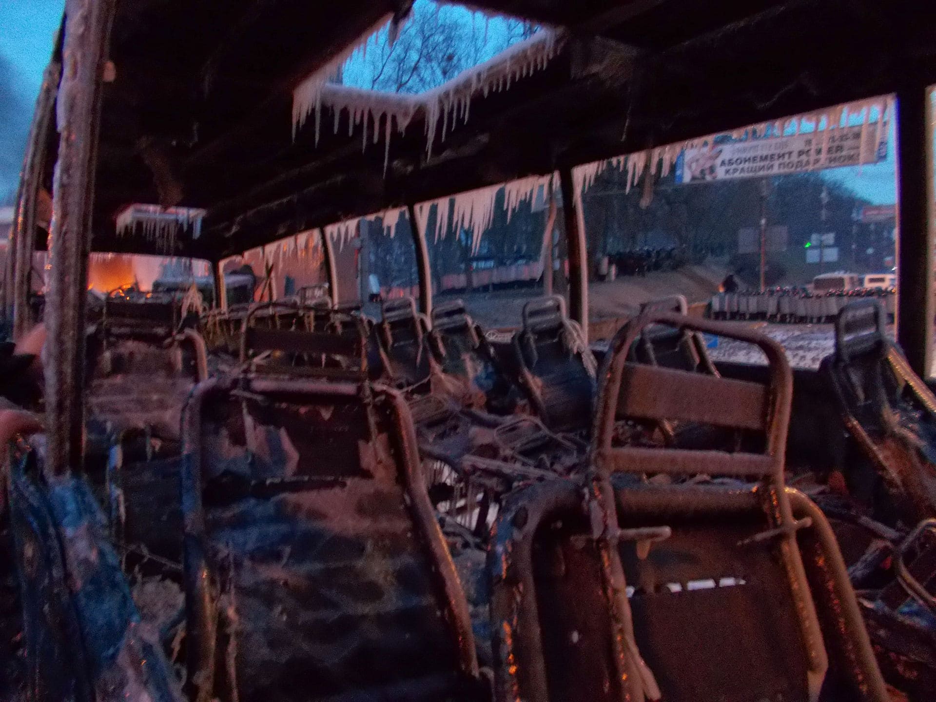 Behind burned bus, militia line
