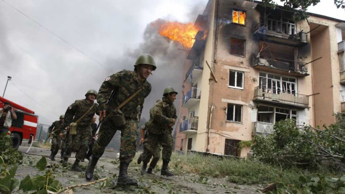 Georgian soldiers run past shelled building in Gori, 80 km from Tbilisi, August 9, 2008