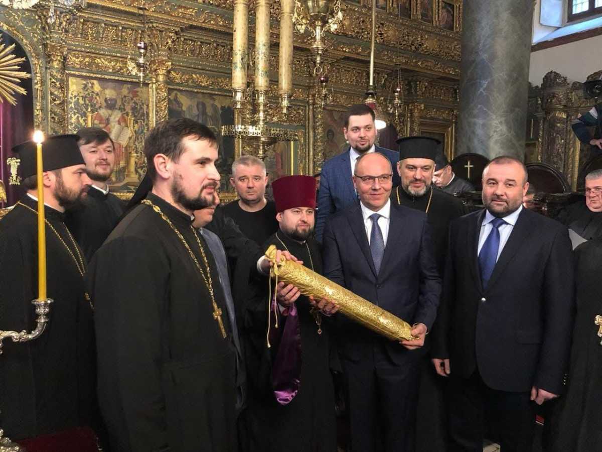 Історичний момент вручення Томосу про Автокефалію ПЦУ. Із сувоєм в руках тодішній голова Верховної Ради Андрій Парубій, поруч із ним його прес-секретар Андрій Ковальов, учасники перемов із Константинополем протоієрей Богдан Гулямов і Олександр Петровський. 6 січня 2019 року