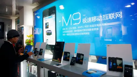 Китайский покупатель испытывает смартфон Meizu M9 в магазине Meizu в Шанхае. Фото: depositphotos