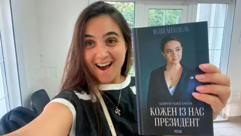 Юлия Мендель с книгой собственного авторства. Фото: facebook/iuliia.mendel.2025