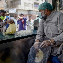 A municipal worker in Karachi (Pakistan) hands out bags of food - part of government efforts. Photo by npr.org